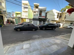 波来古市MoTel HỒ XUÂN的两辆汽车停在大楼前的街道上