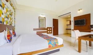 班加罗尔FabHotel Emirates Suites的一间卧室配有一张床和一张书桌