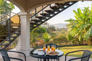 纳西克StayVista's Celeste Villa - Hill-View Retreat with Infinity Pool & Outdoor Jacuzzi的露台上的桌子上摆放着食物和饮料