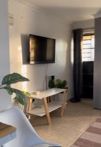 内罗毕Rooftop Studio Apartment - Mirema的客厅配有桌子和墙上的电视