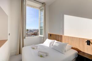 戛纳IMMOGROOM - Apparements luxueux - 2min du Palais - Vue mer - Clim的一间卧室配有一张带白色床单的床和一扇窗户。