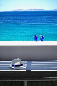 图罗斯Mykonos Riviera Hotel & Spa, a member of Small Luxury Hotels of the World的阳台上的帽子和两杯眼镜