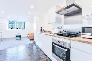 伍尔弗汉普顿Stylish 1 Bed Apartment in Wolverhampton的厨房配有白色橱柜和炉灶烤箱。