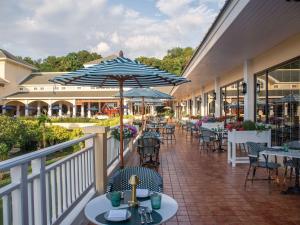 功孟海滩Sofitel Krabi Phokeethra Golf and Spa Resort的阳台配有桌椅和雨伞。