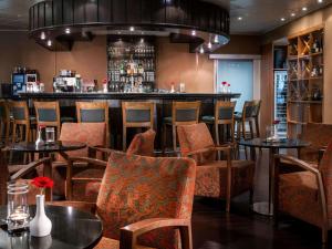 纽伦堡纽伦堡机场瑞享酒店的餐厅内的酒吧配有桌椅