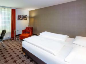 纽伦堡纽伦堡机场瑞享酒店的配有一张床和一把椅子的酒店客房
