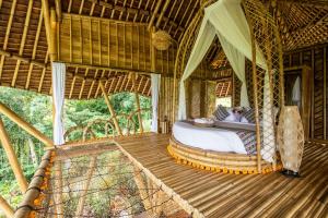 SelatMagic Hills Bali - Magical Eco-Luxury Lodge的一间卧室,在木甲板上配有一张床