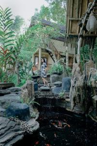 塔巴南Abing Dalem - Villa Durian的站在有池塘的房子前面的人