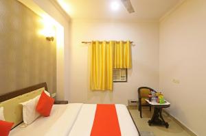 新德里Hotel Samara Near IGI Airport Delhi的一间卧室配有一张黄色窗帘和一张桌子的床