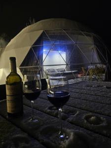 盖贝莱Dream Domes Glamping的桌子上放两杯葡萄酒,还有一瓶葡萄酒