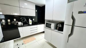 马塞约EDF SEVILHA - Apartamento com 1 suíte climatizada e 2 Banheiros, Sala Climatizada a 300 metros da Beira-Mar de Ponta Verde - EXCELENTE LOCALIZAÇÃO的厨房配有白色橱柜和微波炉