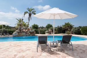 休达德亚桑朱娜达乡村酒店的游泳池旁的一对椅子和一把遮阳伞