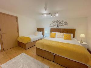 伦敦Angel x Kings Cross Hub的一间卧室配有两张带黄床单的床