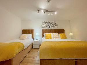 伦敦Angel x Kings Cross Hub的卧室内的两张床,配有黄色床单