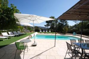 Pugetvery beautiful villa with private pool in the luberon enjoying a magnificent view of the durance valley, located in puget – 10 people.的一个带椅子和桌子的游泳池以及一把遮阳伞