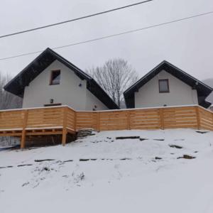 鲁特罗Domki Nad Potokiem的雪中带木栅栏的房子