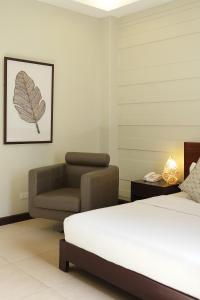 宿务阿尔巴吾诺酒店的一间卧室配有一张床和一把椅子