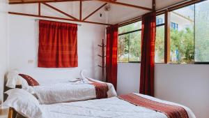 乌鲁班巴The Willow B&B的卧室内的两张床,配有红色窗帘