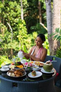 芭东海滩Three Monkeys Villas的坐在桌子上,吃着食物的女人