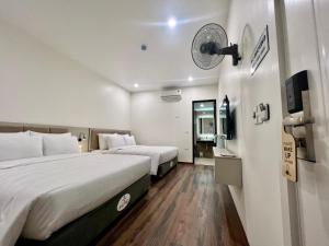 河内Grand Dragon Noi Bai Hotel的酒店客房设有两张床和墙上的时钟。