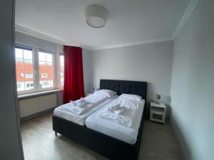 杜亨Haus Nordsee 06的一间卧室配有白色床单和红色窗帘