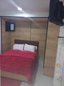 IhaddademStudio lea的一间卧室配有一张带红色棉被的床和一台电视