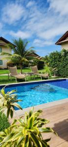 普拉亚多斯卡内罗斯Casa Luxo com piscina privativa próximo a Igrejinha - Com colaboradora e enxoval的庭院内的游泳池,带椅子和树木