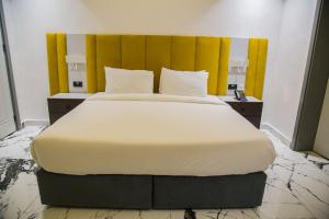 拉各斯The Safron Hotel的一间卧室配有一张带黄色床头板的大床