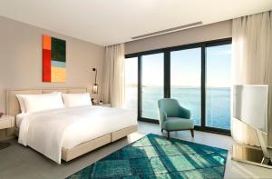 博阿齐奇Le Méridien Bodrum Beach Resort的卧室配有白色的床和蓝色椅子