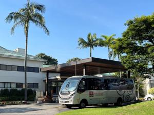 瓜鲁柳斯帕纳比瓜鲁柳斯酒店的停在棕榈树建筑前面的公共汽车