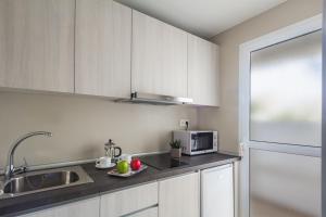 科拉雷侯Playa Park Zensation的厨房配有白色橱柜、水槽和微波炉