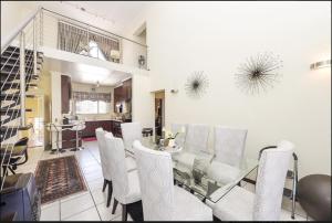 SandtonThe Kanyin的一间设有玻璃桌和白色椅子的用餐室