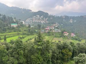 西姆拉The Asha Residency - Majestic Mountain View , Shimla的山丘上的城镇,有树木和建筑