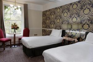 RisleyRisley Hall Hotel的酒店客房,设有两张床和一张红色椅子
