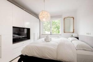 SandweilerLuminous Penthouse with Open Sky Terrace的一间白色卧室,配有床和电视