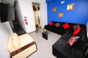 齐克拉约HOSTAL LANCELOT的客厅配有黑色沙发和红色枕头