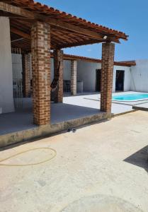 伊塔马拉卡Casa com piscina Forte Orange- Itamaracá的砖砌凉亭,后方设有游泳池