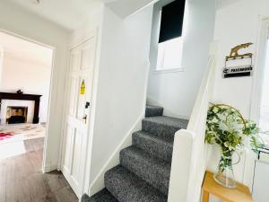 TillicoultryTillicoultry Jupiter Apartment - Scotland Holiday Let的一间铺有灰色地毯的房屋内的楼梯