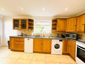 TillicoultryTillicoultry Jupiter Apartment - Scotland Holiday Let的厨房配有木制橱柜、洗衣机和烘干机