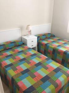 科尔多瓦Gran piso familiar的卧室内的两张单人床和色彩缤纷的被子