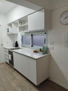 布宜诺斯艾利斯Cabildo Complete Suite的厨房配有白色橱柜和墙上的时钟