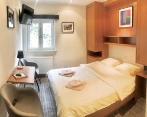 博福特Hotel Auberge Rustique的一间卧室配有一张床、一张书桌和一个窗户。