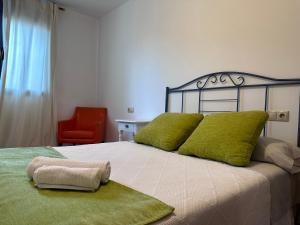 蓬费拉达Suite Rigel的一间卧室配有一张带绿色枕头的床和一张红色椅子
