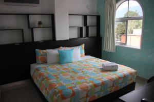 MéridaHOTEL MILLA SUITES MERIDA的一间卧室配有一张带橙色和蓝色棉被的床