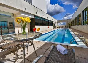 巴西利亚Flat 315 - Comfort Hotel Taguatinga的游泳池旁带花瓶的玻璃桌