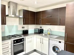 伦敦London 2Bedrooms 2Bathrooms, Balcony, Parking, Lovely South Woodford的厨房配有白色橱柜、洗衣机和烘干机