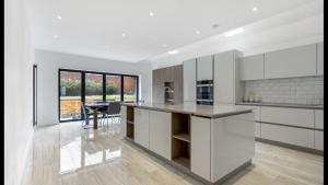 East BarnetNewly refurbished 3 bedroom property in north london的一间带白色橱柜的厨房和一间带桌子的用餐室