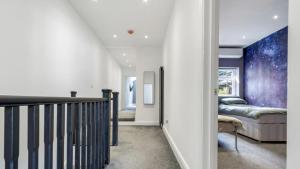 East BarnetNewly refurbished 3 bedroom property in north london的走廊上设有楼梯,房间内设有一张床