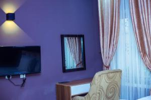 AbeokutaÌtùnú at Molara's Villa的一间卧室设有紫色的墙壁、一台电视和一把椅子