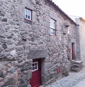 利尼亚雷斯Recanto da Pedra的一座石头建筑,设有红色的门和两扇窗户